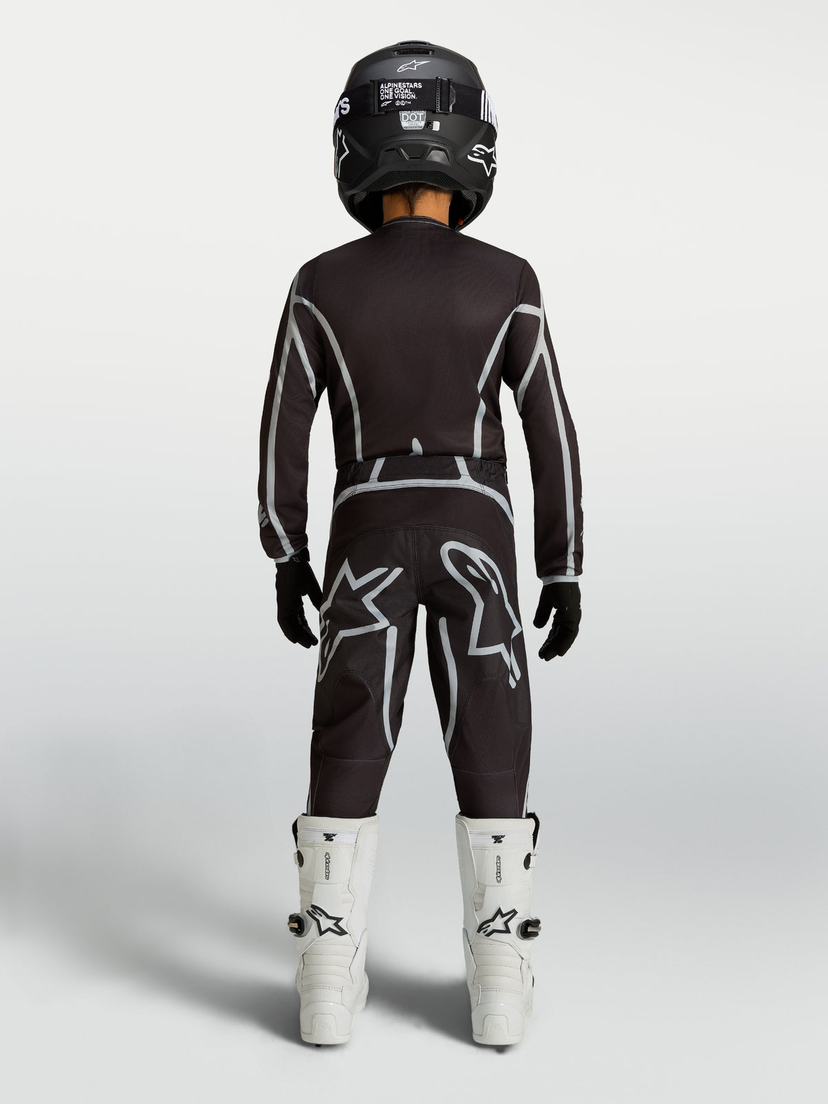 Alpinestars camisola e conjunto juventude Fluid Apex V2, kit de motocross preto e prateado com botas brancas, vista traseira.