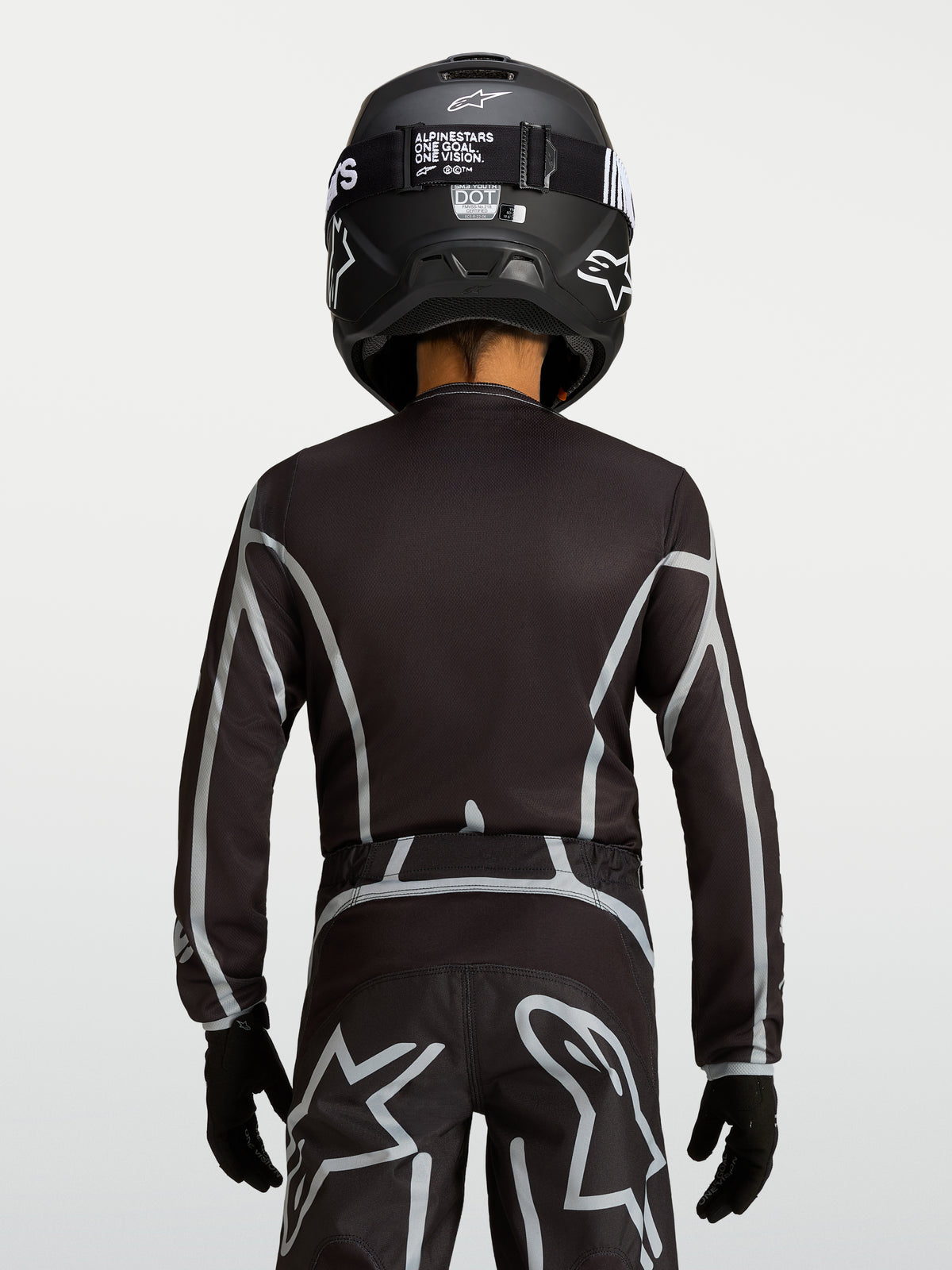 Camisola Alpinestars Fluid Apex V2 Jovem, camisola de motocross preta e prateada, vista traseira com ajuste ergonómico e cobertura traseira estendida