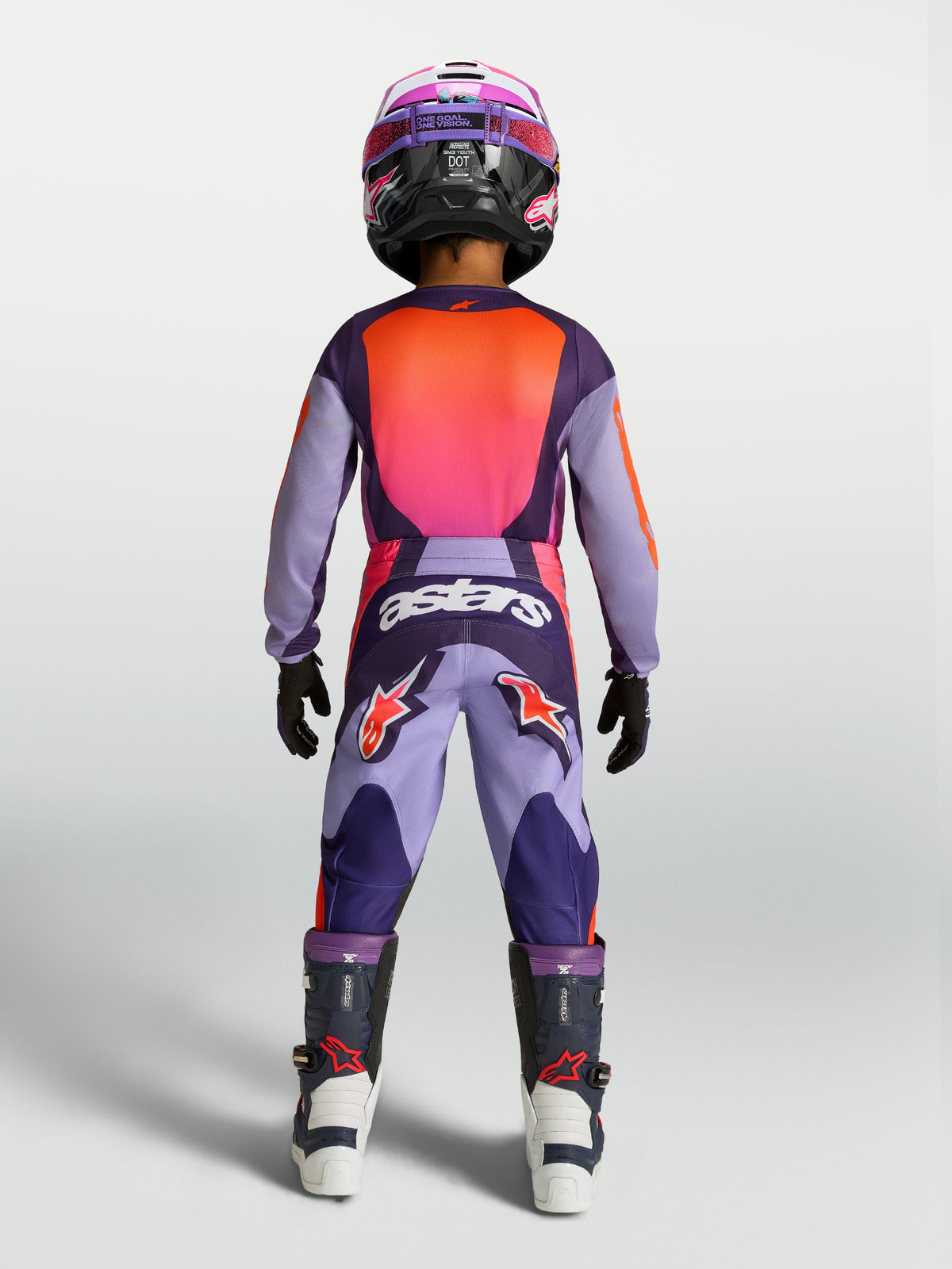 Conjunto Alpinestars Fluid Hunt jovem, equipamento de motocross roxo e rosa fluo, vista traseira em piloto jovem.