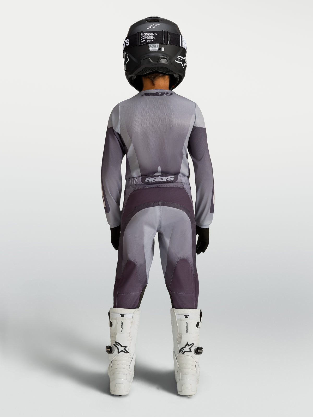 Alpinestars Juventude Fluid Amber Gear Set 2027, conjunto de motocross cinzento e roxo, vista traseira no piloto.