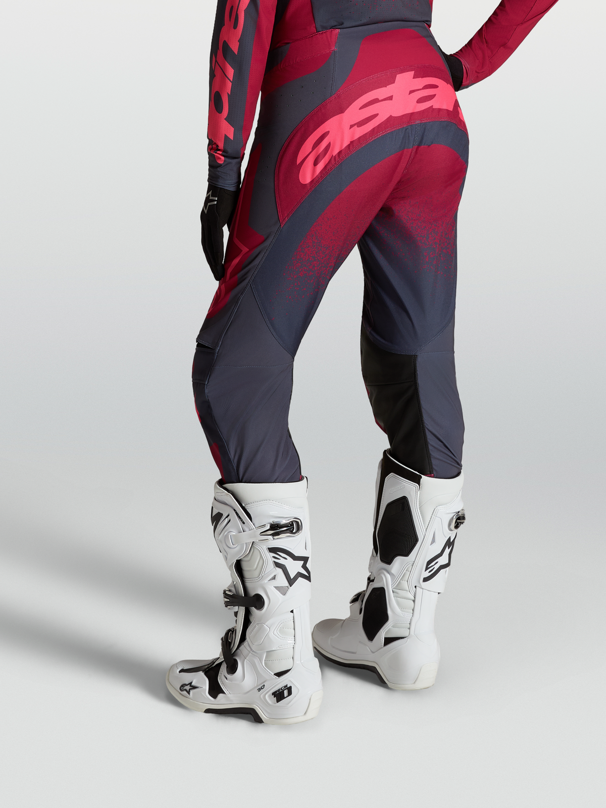 Alpinestars Stella Techstar Swan, calças de motocross para mulher, carmesim e cinzento escuro, com botas Tech 10 brancas.