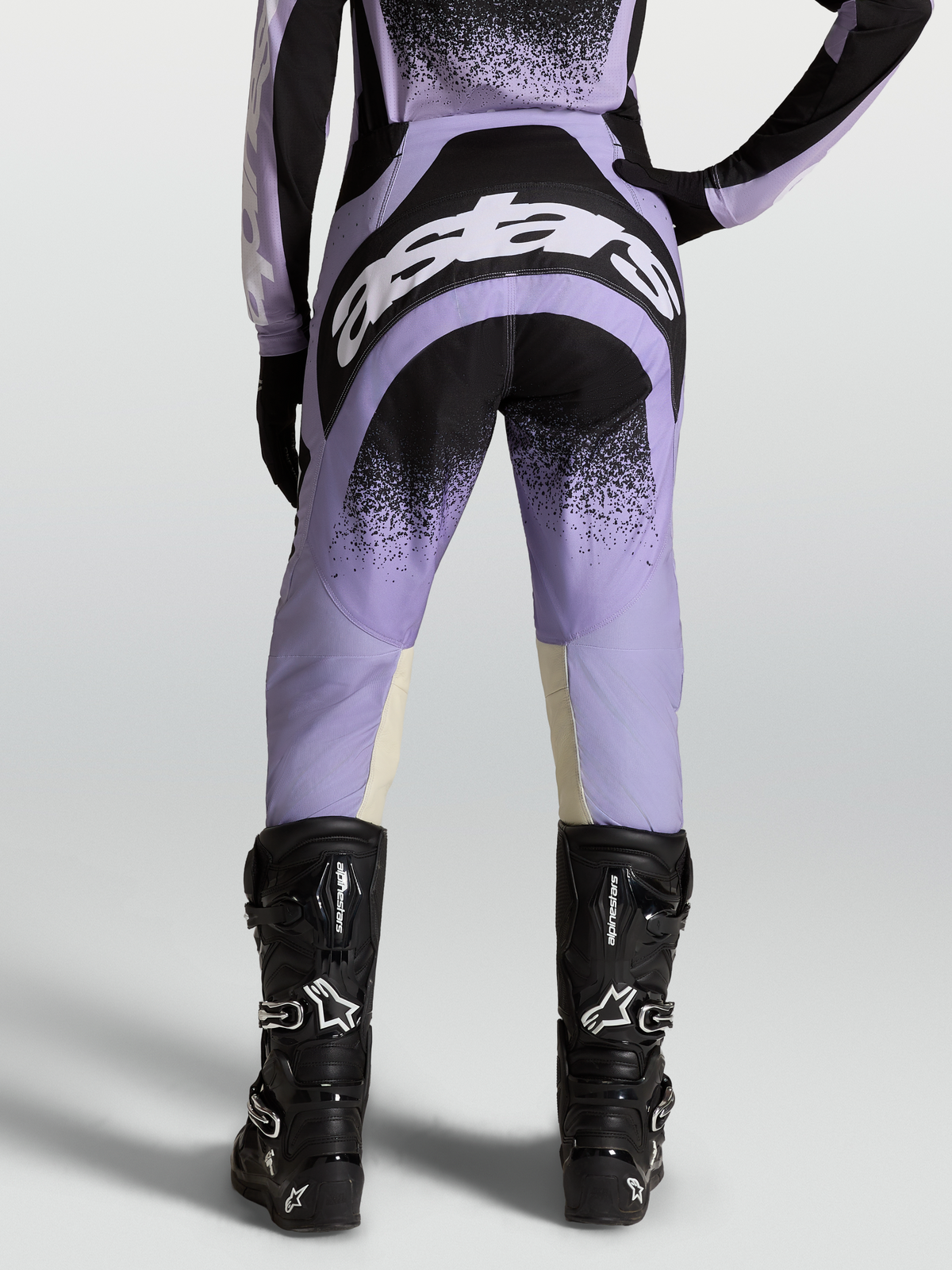 Alpinestars Calças Stella Techstar Swan, equipamento de motocross para mulher, roxas e pretas, vista traseira com botas pretas.