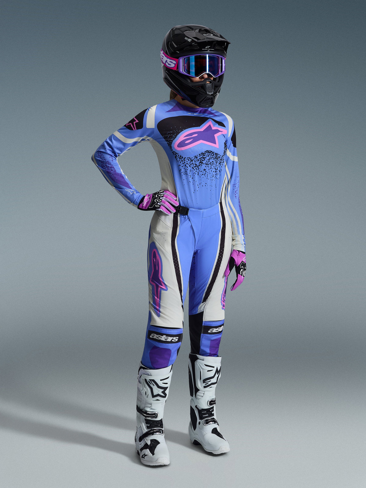Conjunto de Equipamento Alpinestars Stella Techstar Nomur 2026, equipamento de motocross para mulher, com camisola azul clara e logótipo Astar cor-de-rosa, calças a condizer com painéis brancos e pretos, capacete preto com óculos cor-de-rosa e roxos, luvas cor-de-rosa e botas de motocross brancas