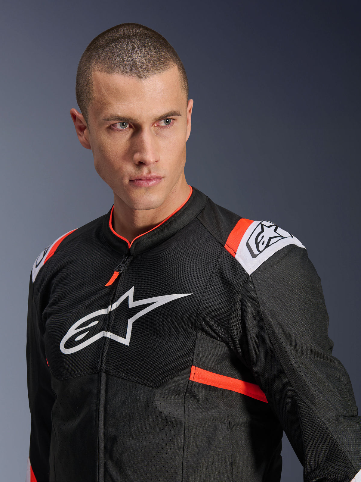 Casaco Alpinestars T-SPS Air v2, preto com detalhes em branco e vermelho fluo, construção em malha têxtil para fluxo de ar, logótipo Alpinestars branco grande no peito, vestido por um modelo, estilo de condução desportiva urbana