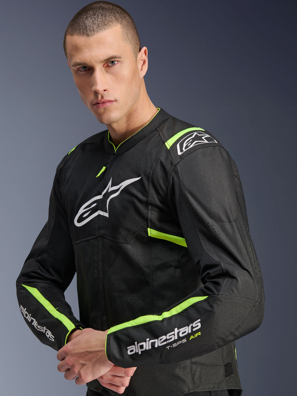 Casaco Alpinestars T-Sps Air V2, preto e amarelo néon, casaco de motociclismo têxtil usado por um modelo, com painéis de malha técnica para fluxo de ar, logótipo Alpinestars branco no peito e detalhes em amarelo néon nos ombros e mangas.