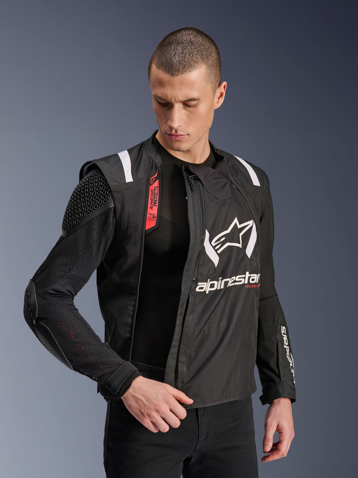 Casaco Alpinestars T-Stunt Air, casaco de motociclismo em preto e branco, usado por modelo masculino, destacando a construção modular em malha e proteções internas expostas no ombro e cotovelo, logótipo Alpinestars no peito, funcionalidade Tech-Air Ready, corte desportivo para condução em estrada