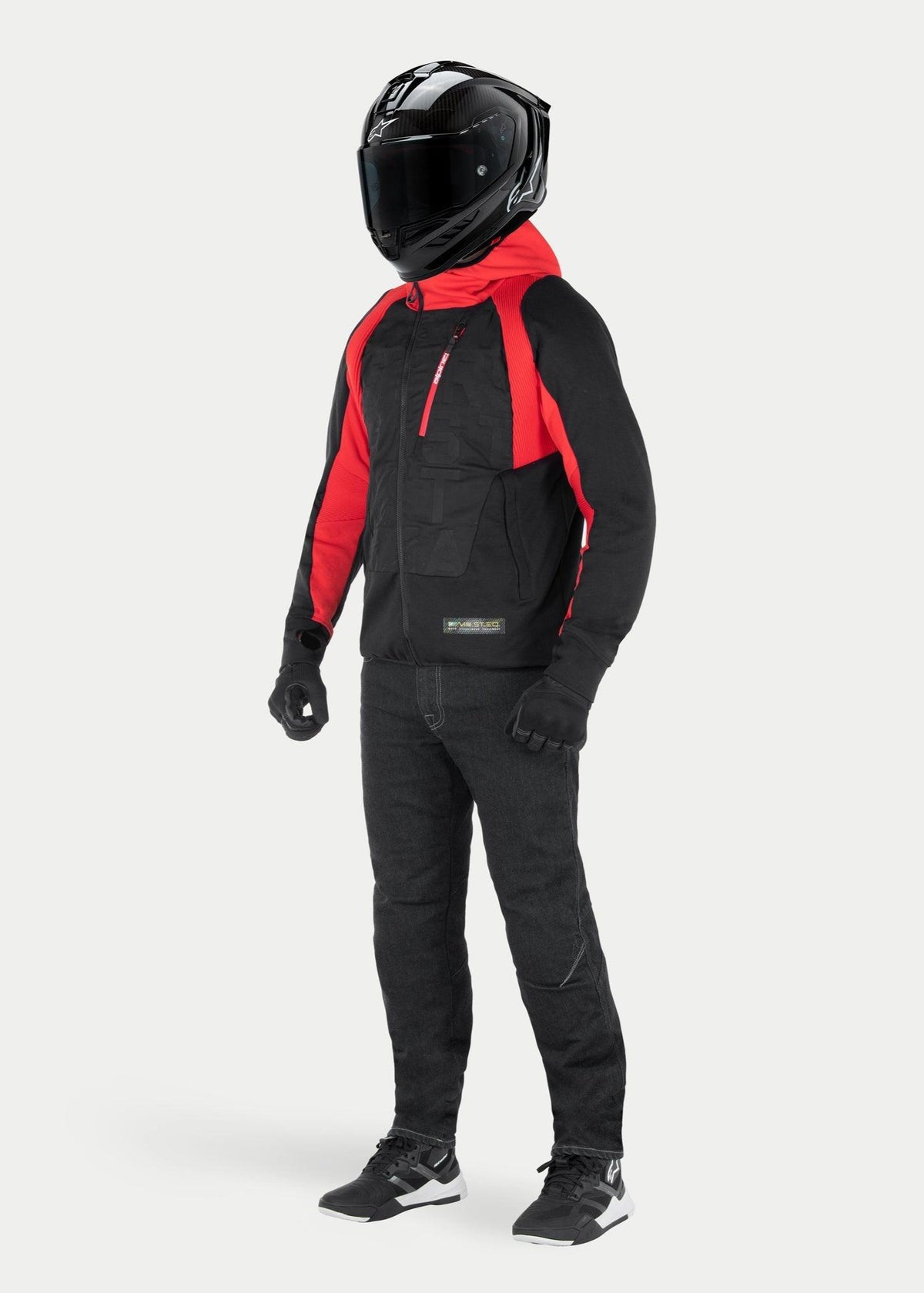 Alpinestars MO.ST.EQ Hybrid Hooded Jacket em Black Flame Red, casaco de motociclismo urbano com capuz e detalhes nos ombros em vermelho, usado com capacete integral preto e calças de condução, design contemporâneo inspirado em streetwear