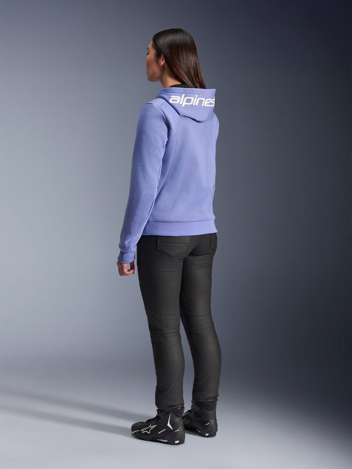 Alpinestars Woman Stella Chrome V2 Sport Hoodie, Blue Violet, rear view showing white branding on the hood, worn with black riding pants and black motorcycle boots, casual urban motorcycle gear