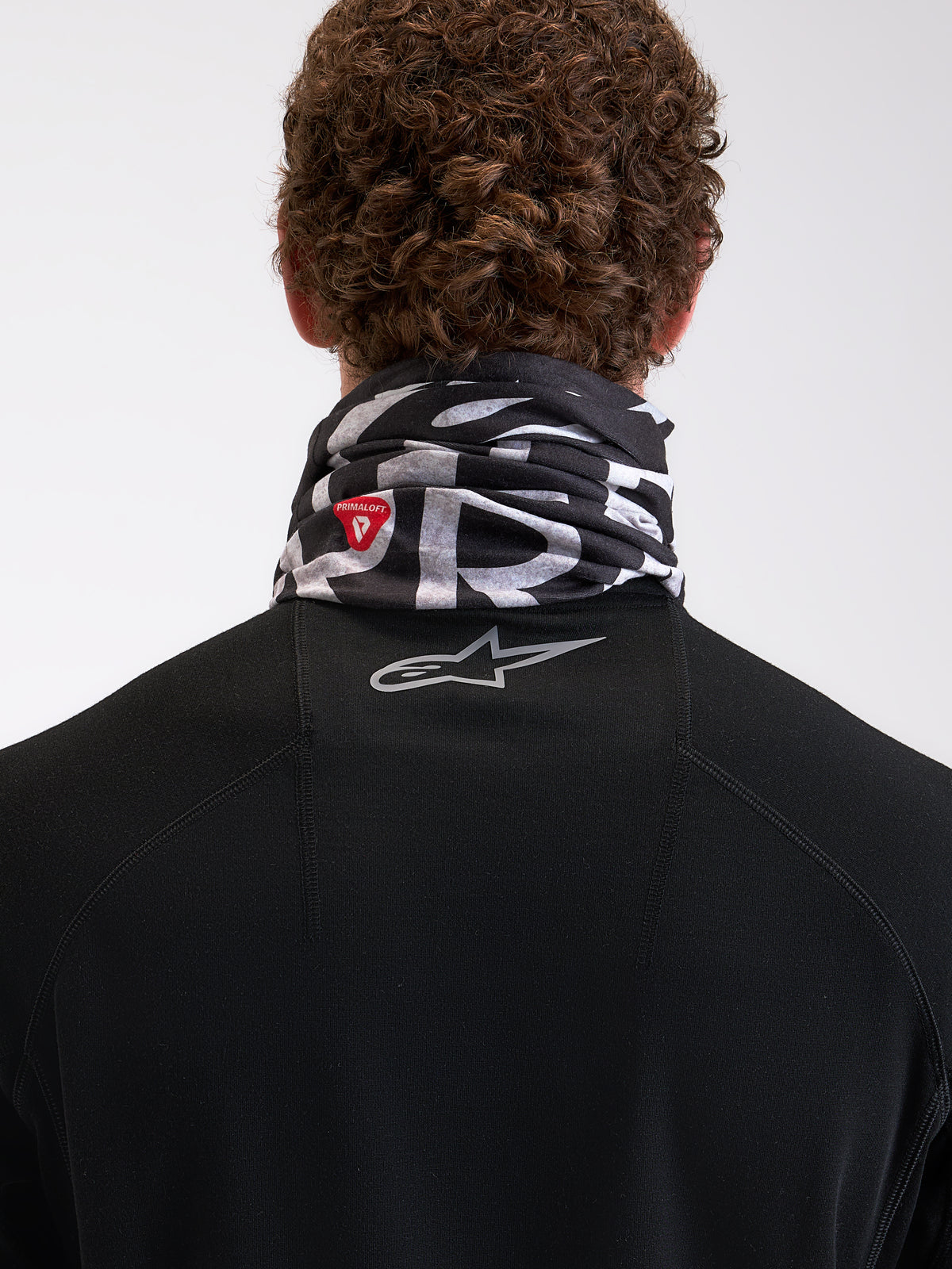 Alpinestars Buff All Terra Primaloft Neck Tube, gola térmica de moto para tempo frio, preta e cinzenta, vista traseira num modelo com logótipo PrimaLoft e branding Astar refletor