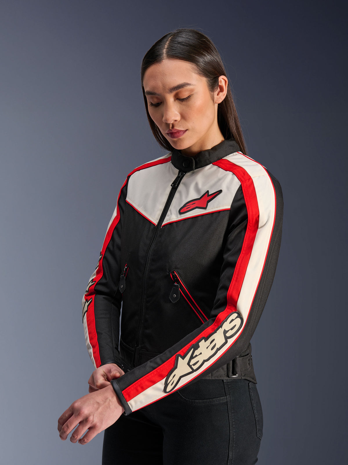 Alpinestars Stella T-Dyno WR Jacket, casaco têxtil de motociclismo para mulher, preto, cru e vermelho brilhante, design de inspiração vintage com logótipo vermelho da Alpinestars no peito e marca na manga, vestido por uma modelo num estúdio