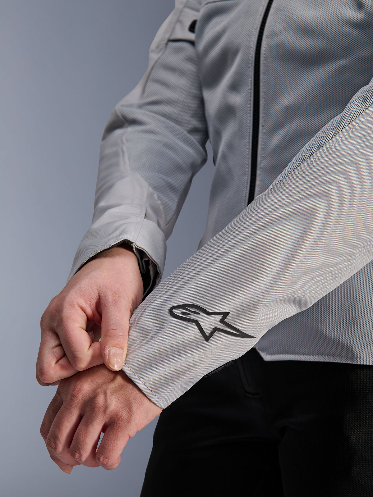 Pormenor do Casaco Alpinestars Stella C-1 Air em prateado, com construção em malha técnica e um logótipo preto da Alpinestars na manga esquerda, casaco de motociclismo urbano para mulher com marca refletora.