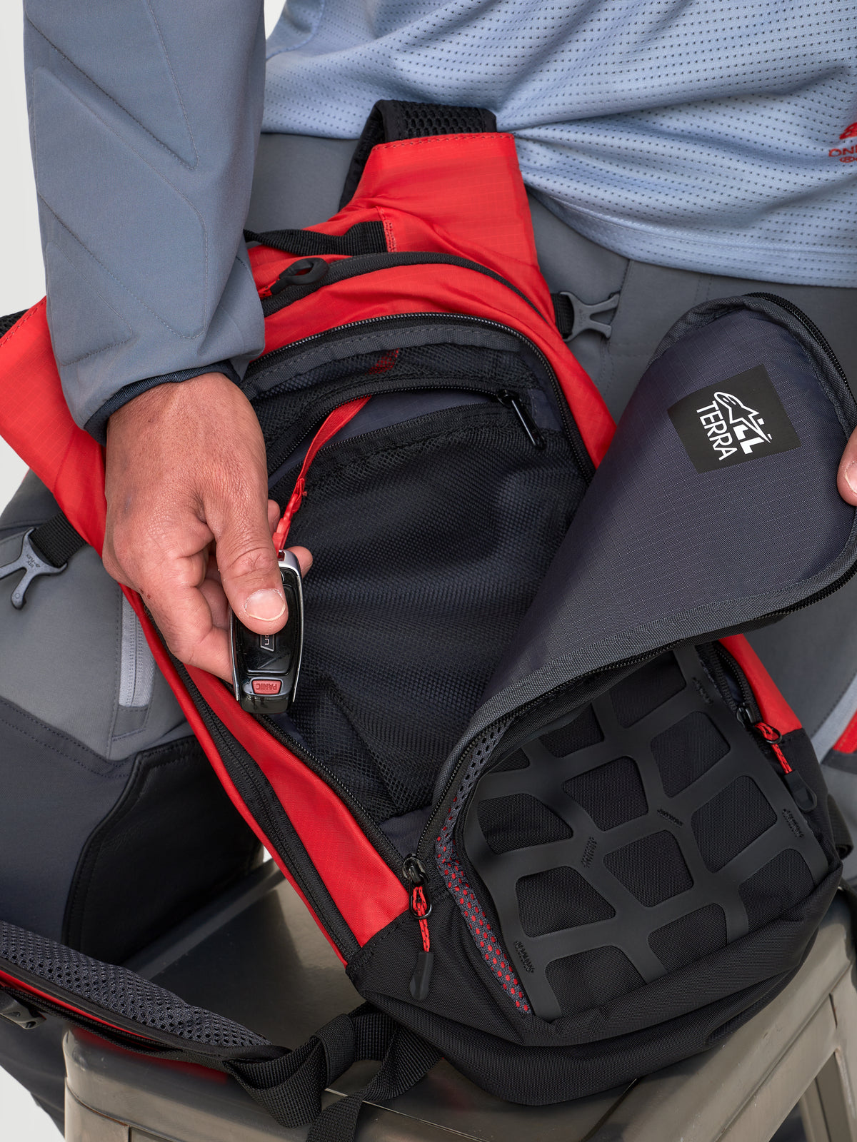 Alpinestars Mochila AT-9, mochila de motocross, vermelha e preta, vista em pormenor a mostrar os compartimentos de arrumação organizados e o fecho de correr num modelo