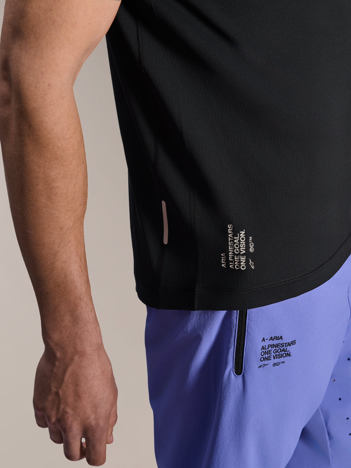 Alpinestars A-Aria Lite Short em Baja Blue, calções de BTT, com a inscrição 'One Goal. One Vision.' estampada e bolso com fecho de correr, combinados com uma camisola A-Aria Switch preta, vista em grande plano de equipamento técnico de ciclismo.