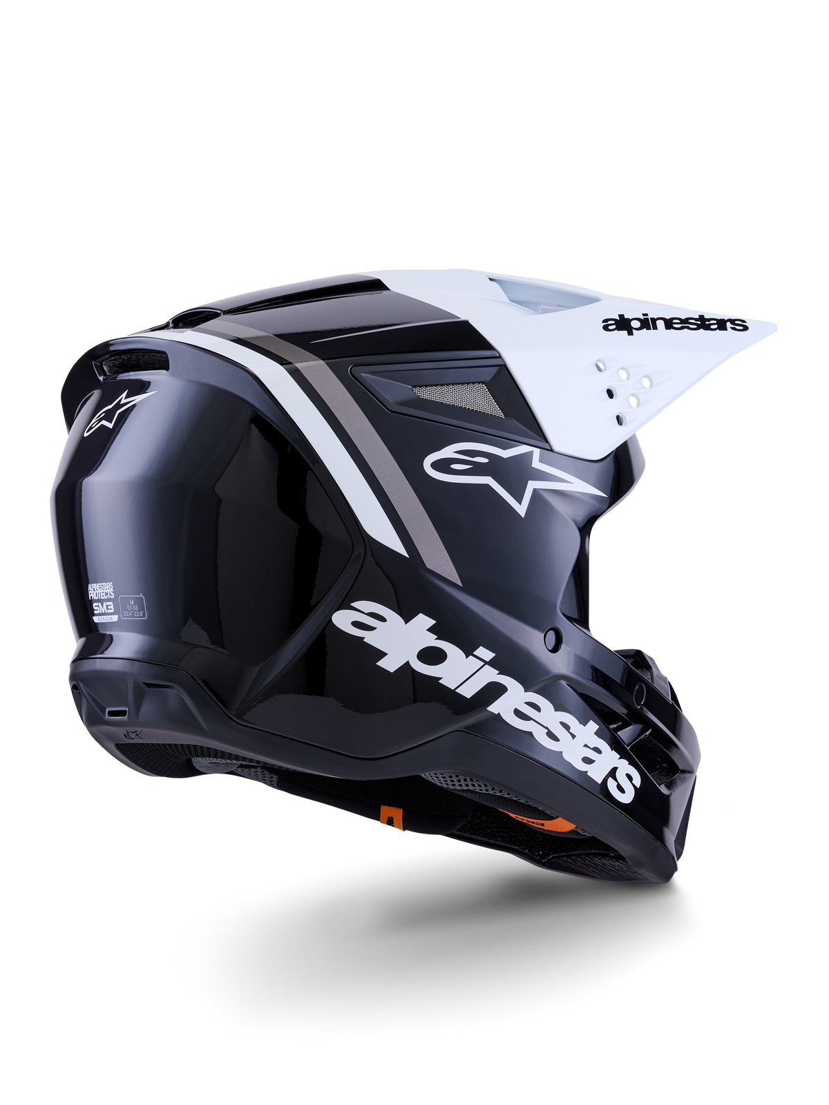 Capacete Alpinestars S-M3 Radium, capacete de motocross, preto, branco e cinzento brilhante, vista lateral traseira com viseira branca, logótipo Alpinestars em destaque na lateral e na traseira, calota aerodinâmica com malha de ventilação, concebido para motocross todo-o-terreno e enduro