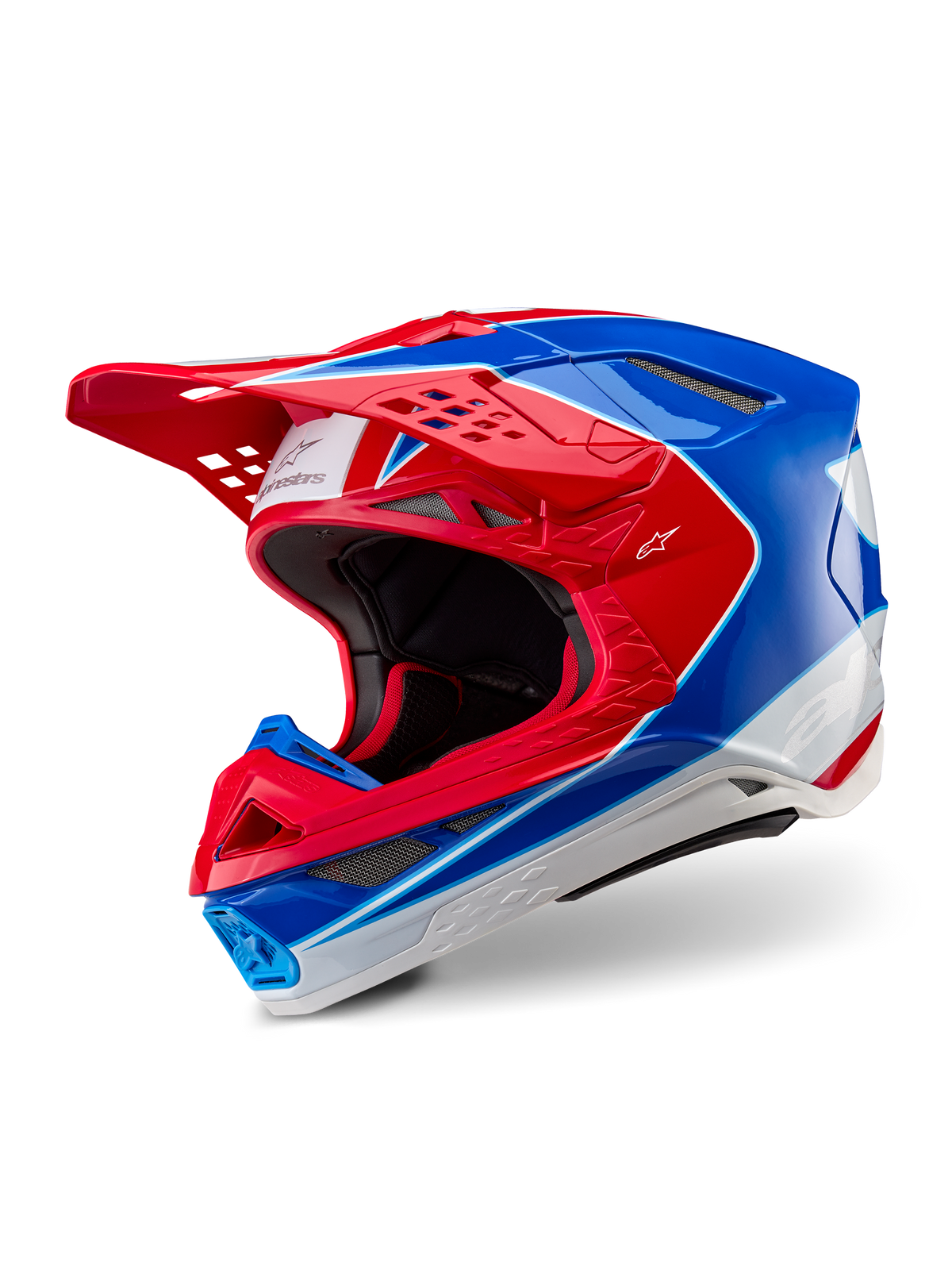 Capacete Alpinestars Supertech M10 Aeon, capacete de motocross, vermelho e azul brilhante, vista em três quartos mostrando a calota aerodinâmica com múltiplas aberturas de ventilação, pormenores gráficos em branco e vermelho, logótipo Alpinestars na viseira e na lateral, equipamento de corrida profissional todo-o-terreno