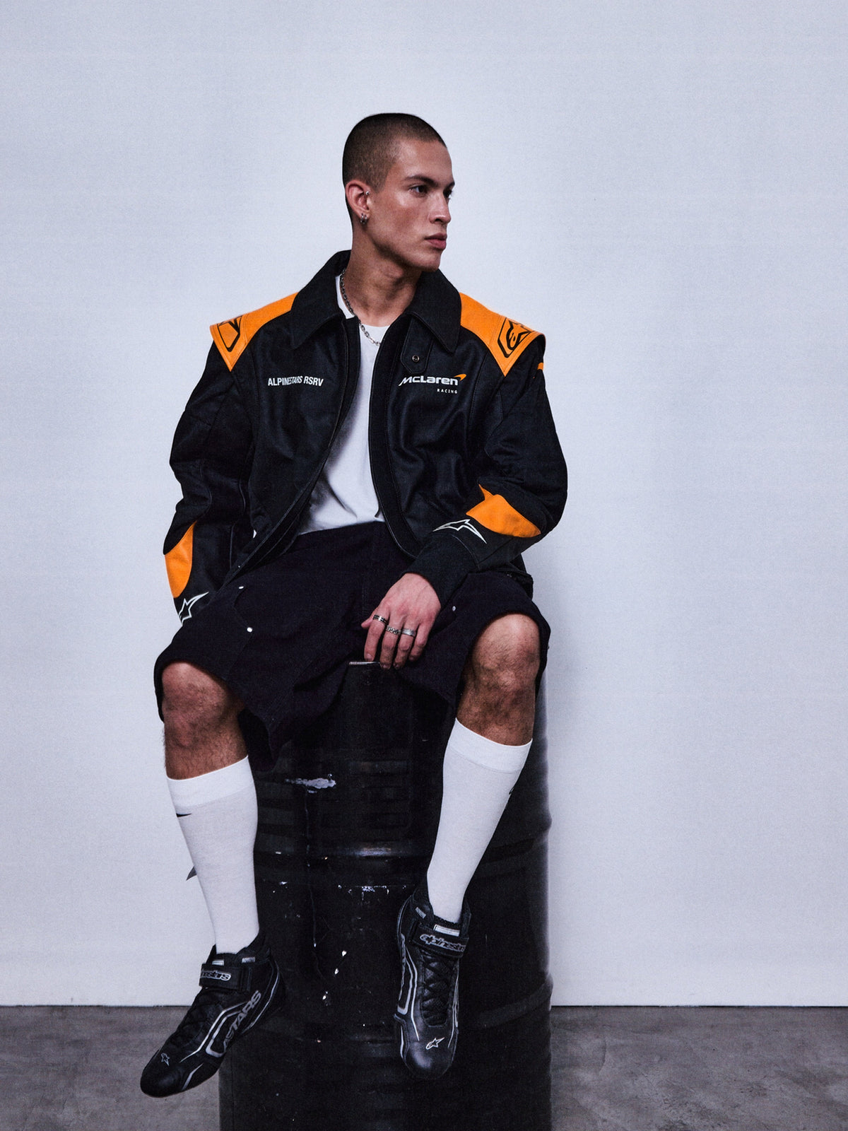 Alpinestars RSRV Track Star, casaco de pele para moto, preto e laranja, estilo desportivo urbano, com logótipos e texto no peito, usado sobre fundo branco