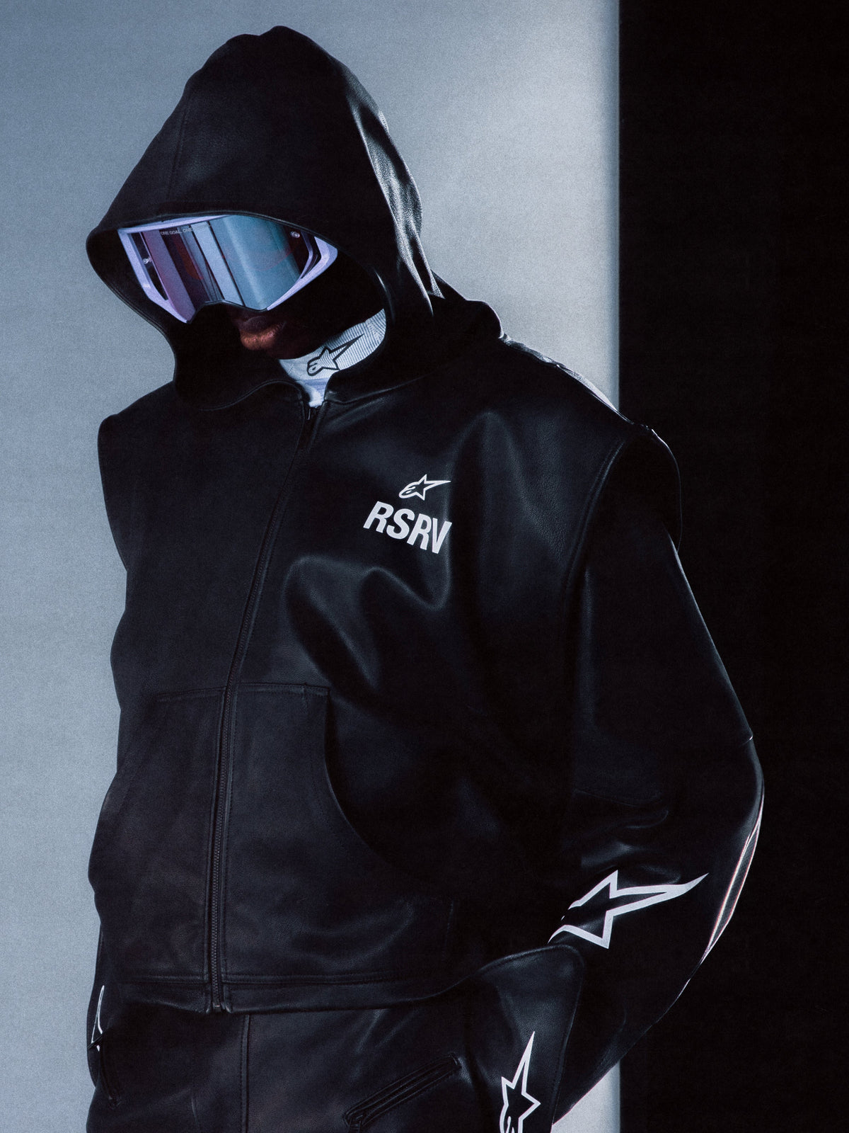 Alpinestars RSRV Axis Leather Hoodie, casaco de couro com capuz preto, logótipo RSRV e estrela, design futurista com textura brilhante, estrelas brancas nas mangas