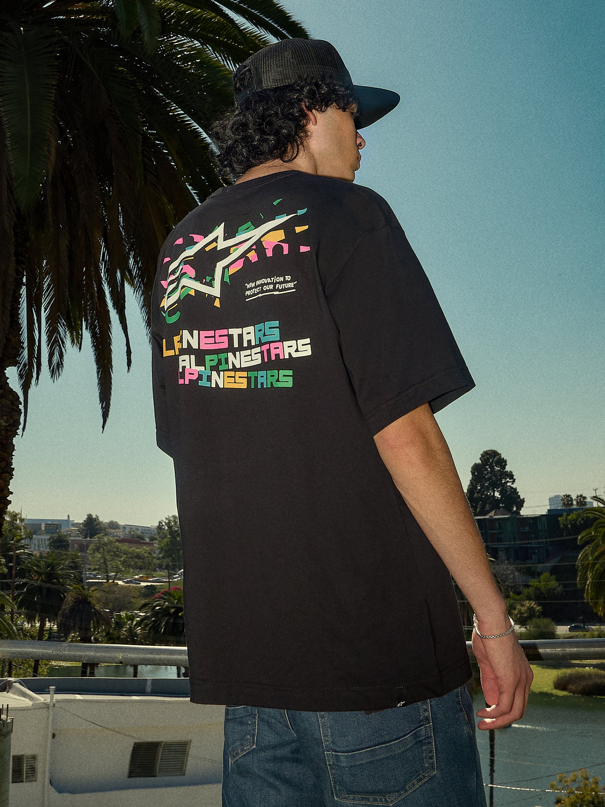 Alpinestars Wild Oversized CSF Tee, t-shirt de manga curta, preta, logótipo Astars multicolorido vibrante nas costas, corte oversized, fotografia de estilo de vida casual streetwear com palmeiras