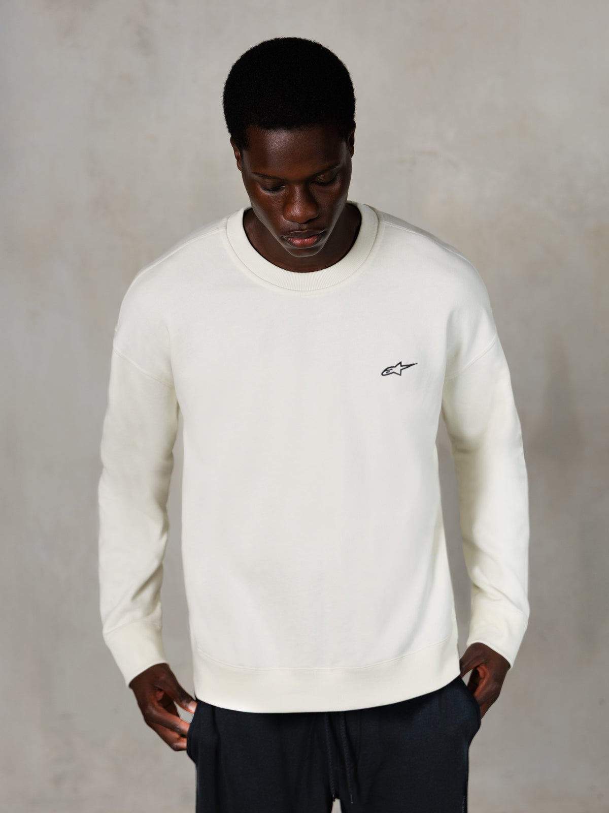 Alpinestars Essentials Ageless Crew, sweatshirt de gola redonda, Off White, pequeno logótipo Alpinestars preto no peito, usada por um modelo, estilo casual lifestyle streetwear, fleece macio premium