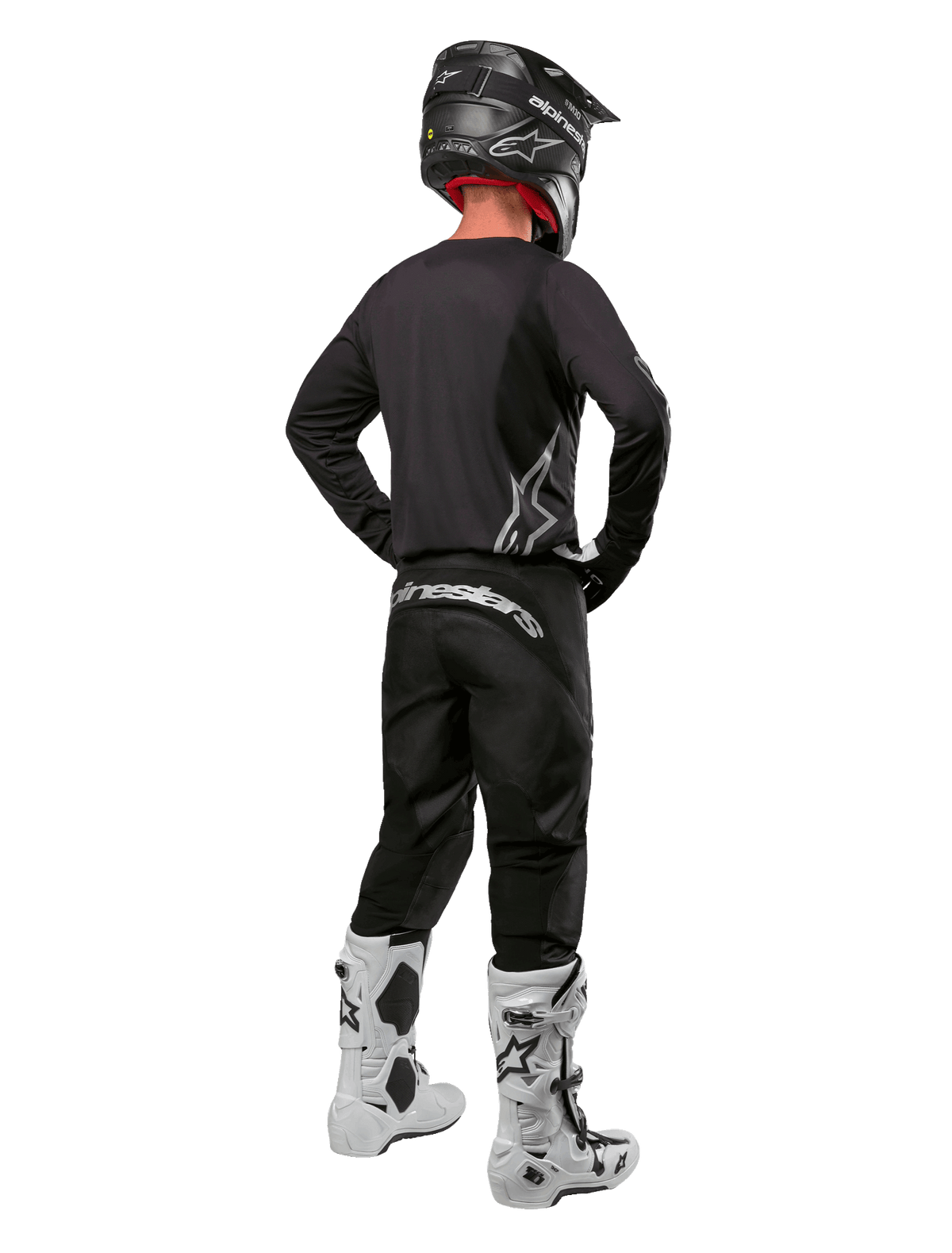 Conjunto de Equipamento Alpinestars Fluid Graphite 2024, piloto de motocross visto de costas, camisola e calças em cinzento grafite com logótipos Alpinestars prateados, capacete preto e botas de motocross brancas, equipamento de ajuste atlético para todo-o-terreno
