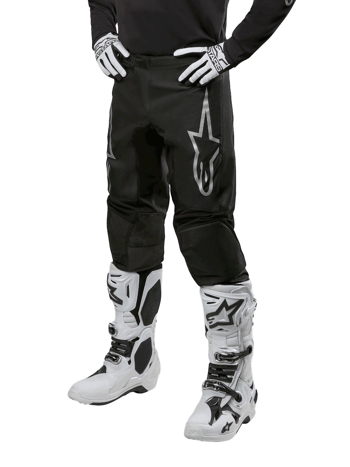 Alpinestars 2024 Fluid Graphite Pants, calças de motocross, pretas e prateadas, com logótipo Alpinestars prateado na coxa, apresentadas com botas e luvas de motocross brancas, concebidas para corridas de motas todo-o-terreno