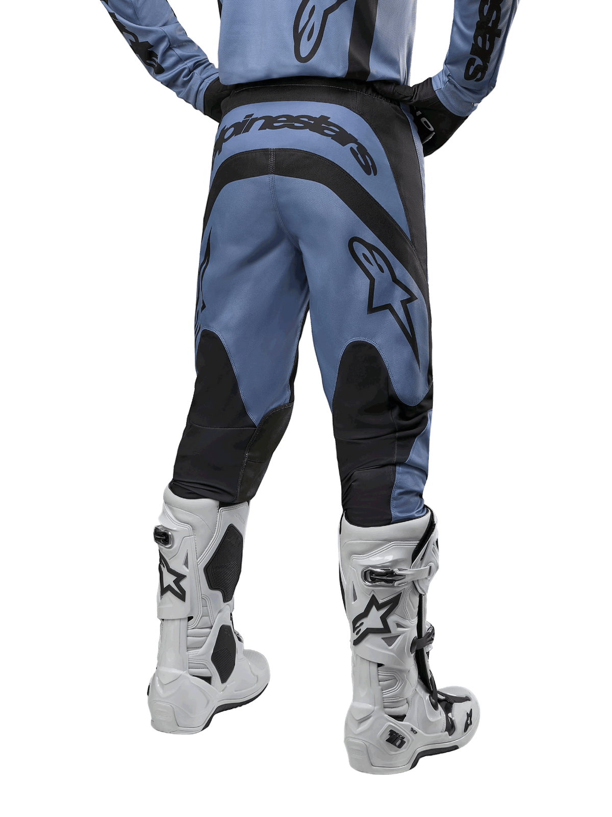 Alpinestars 2024 Fluid Lurv Pants, calças de motocross, azul claro e preto, vista traseira com painéis reforçados pretos e logótipo grande da marca, combinadas com botas de motocross brancas e pretas, equipamento de competição profissional para todo-o-terreno