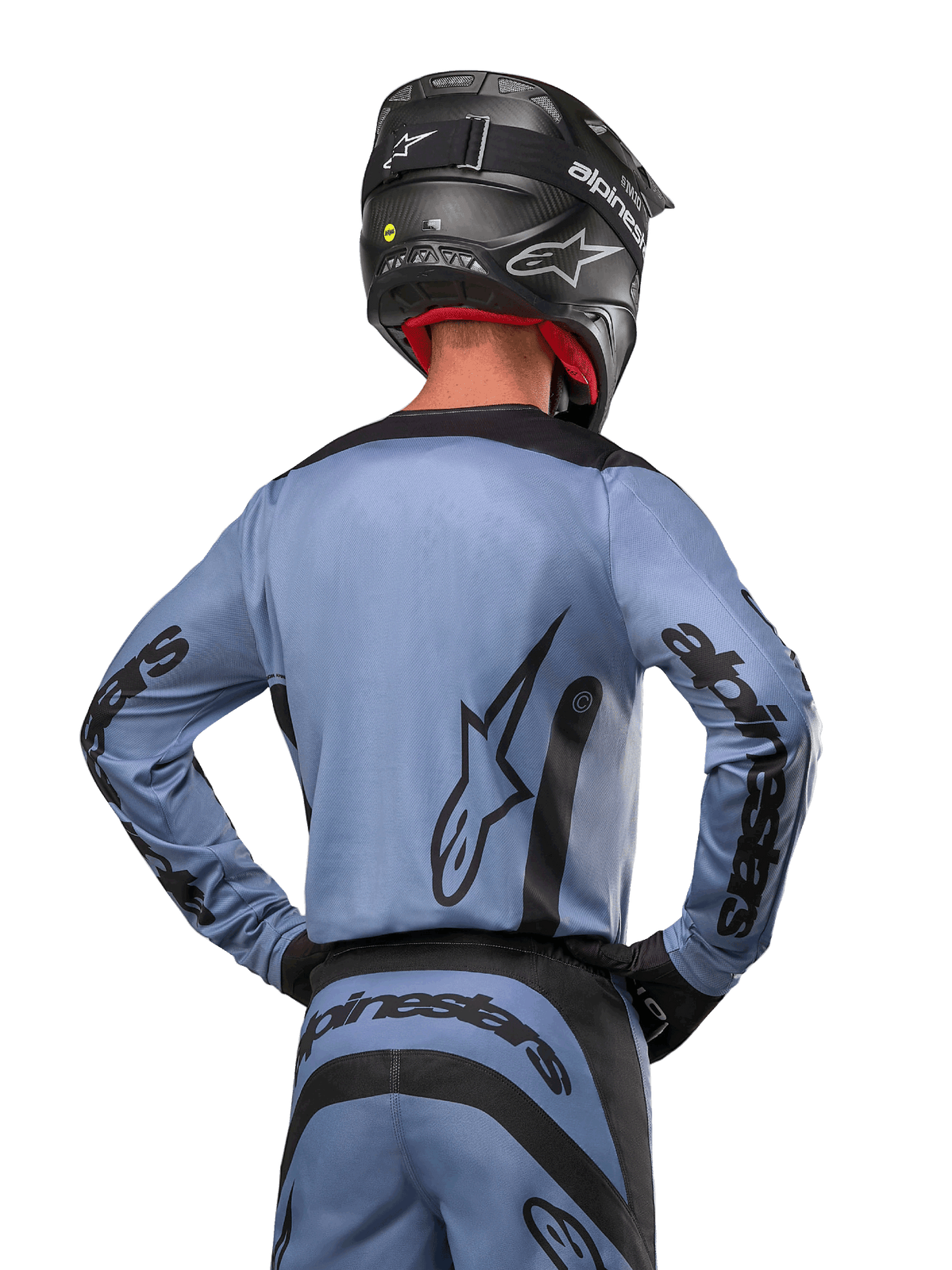 Alpinestars 2024 Fluid Lurv Jersey, camisola de motocross, azul claro e preto, vista traseira do piloto mostrando o grande logótipo de estrela e a marca nas mangas, usada com um capacete preto e calças de todo-o-terreno a condizer, vestuário de corrida profissional