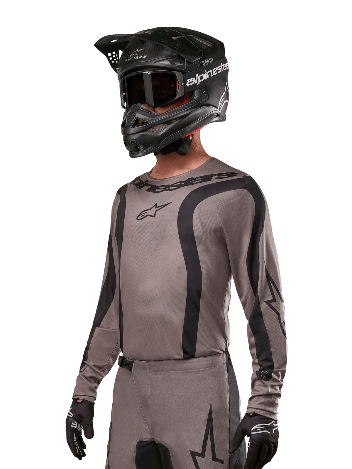 Alpinestars 2024 Fluid Lurv Jersey, camisola de motocross, Mud Black e cinzento, design de manga comprida com riscas pretas curvas e logótipos, usada com calças a condizer e um capacete de motocross preto, conjunto de corrida off-road coordenado