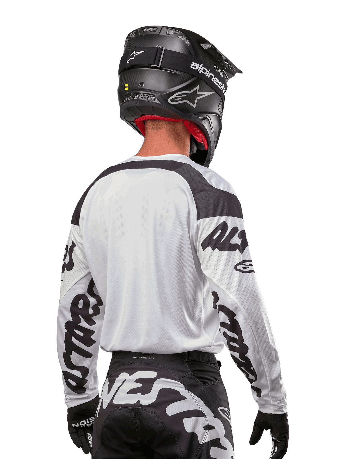Camisola Alpinestars 2024 Racer Hana, branca e preta, vista traseira mostrando o ajuste ergonómico e logótipos de destaque nas mangas, combinada com um capacete de motocross preto e calças pretas e brancas a condizer, equipamento de alta performance para condução off-road