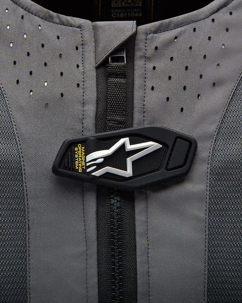 Detalhe do Airbag Alpinestars Tech-Air 5, aba magnética com logótipo de estrela branco em tecido perfurado cinzento.