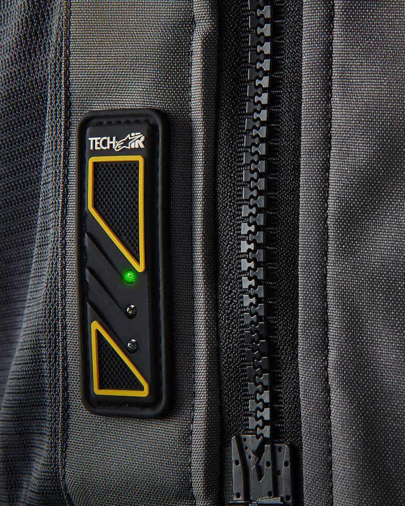 Painel LED do Airbag Tech-Air 5 num colete têxtil cinzento escuro, com luz verde brilhante e fecho de correr preto.