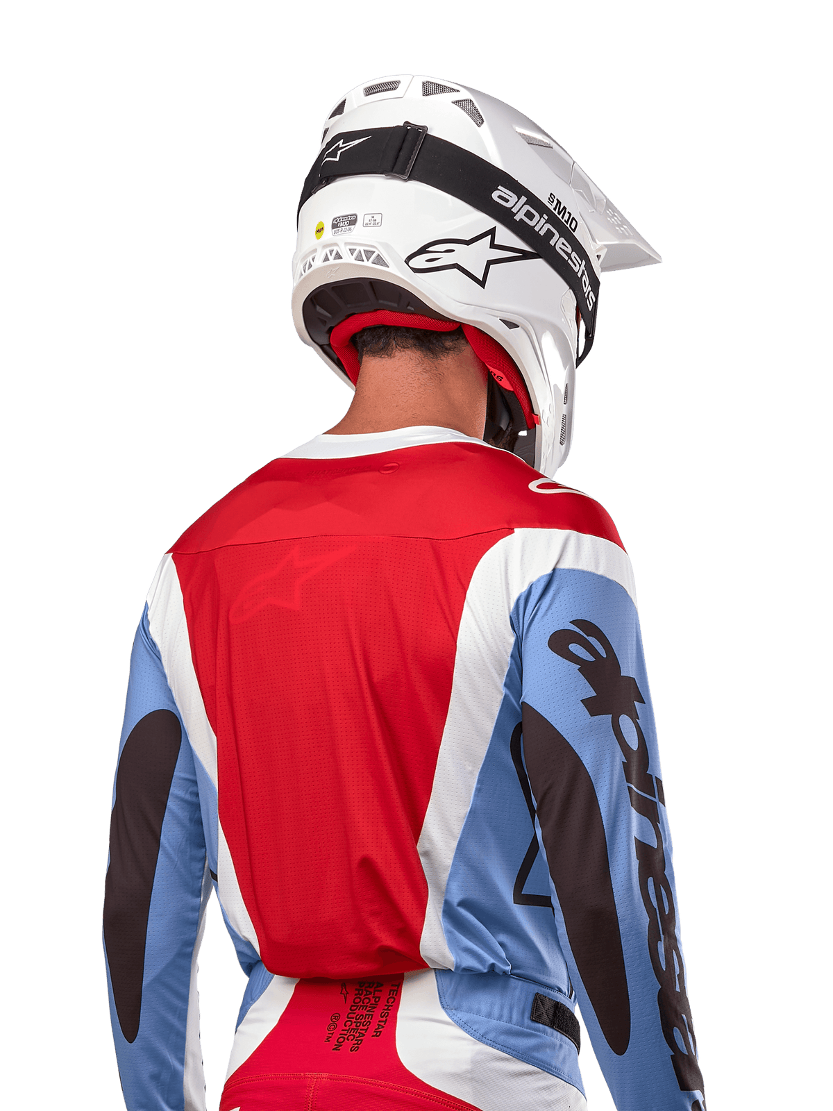 Camisola Alpinestars Techstar Ocuri 2024, camisola de motocross, azul claro, vermelho Mars e branco, vista traseira do piloto com capacete branco e óculos pretos, apresenta logótipos pretos de destaque nas mangas e corte ergonómico de corrida para performance em todo-o-terreno.