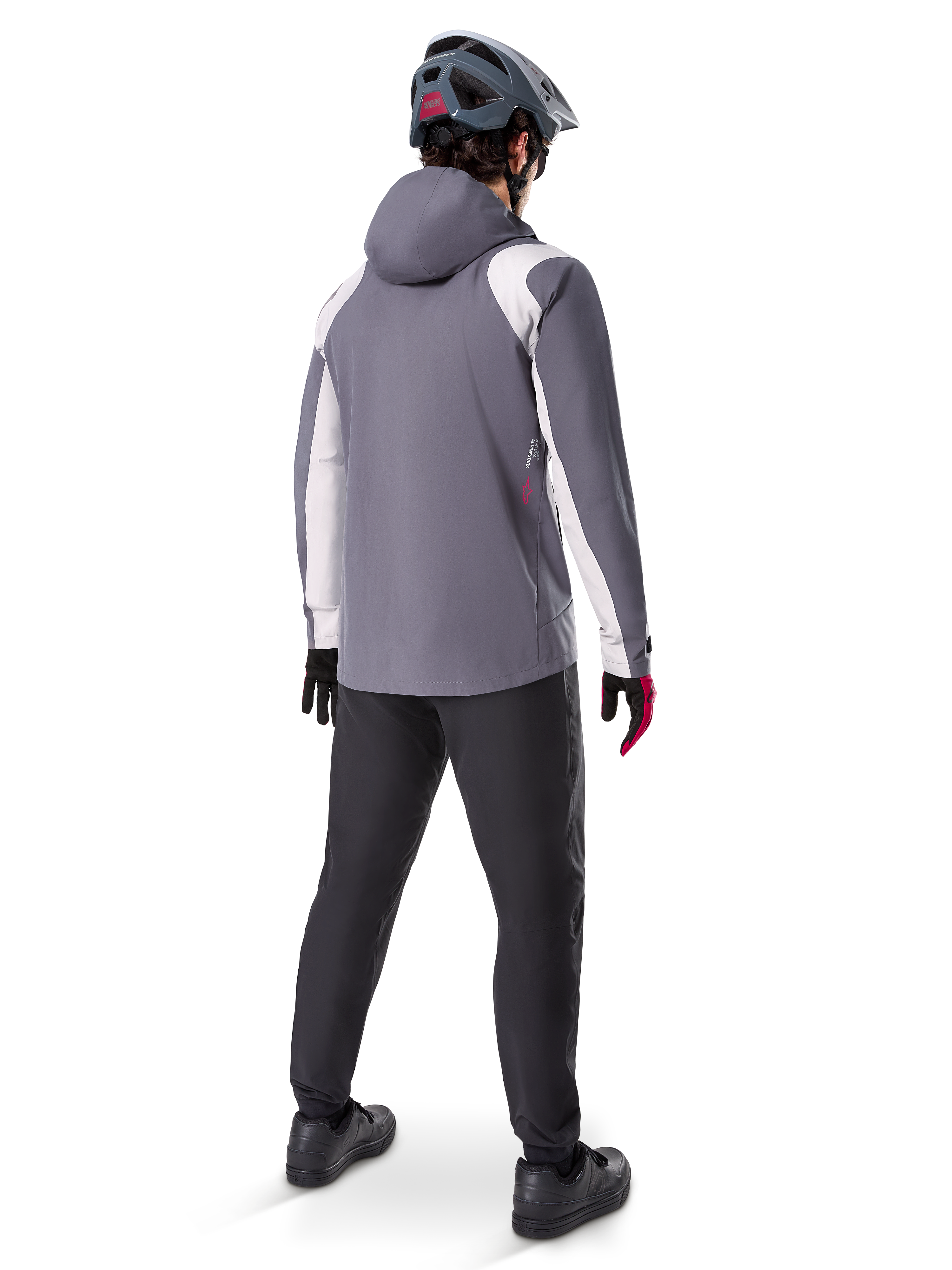 Alpinestars A-Dura Rain Jacket, Mountain Bike Jacket, Dark Titanium Gray with white panels, back view of rider wearing matching gray helmet and black pants, technical outdoor gear for wet weather