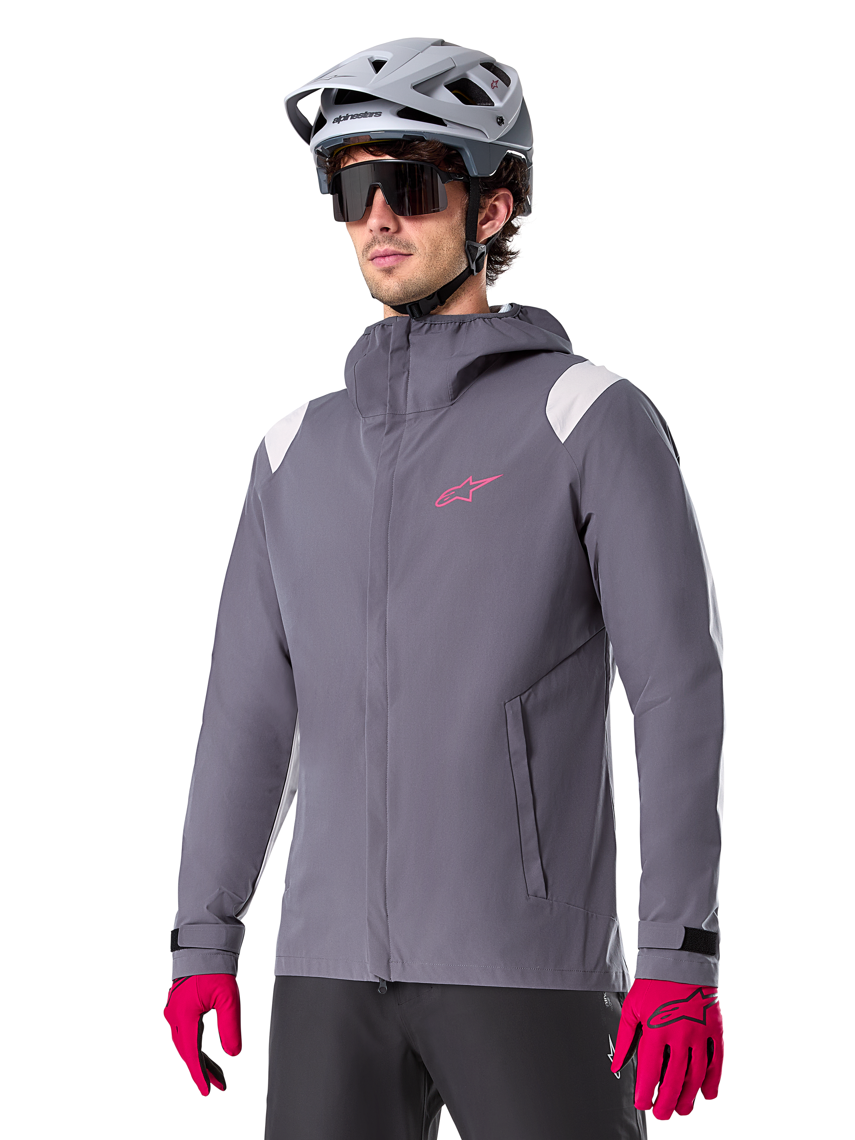 Alpinestars A-Dura Rain Jacket, casaco impermeável para BTT, cinzento titanium escuro com logótipo cor-de-rosa e detalhes brancos nos ombros, design com capuz e bolsos frontais, usado com luvas cor-de-rosa e capacete de ciclismo cinzento claro