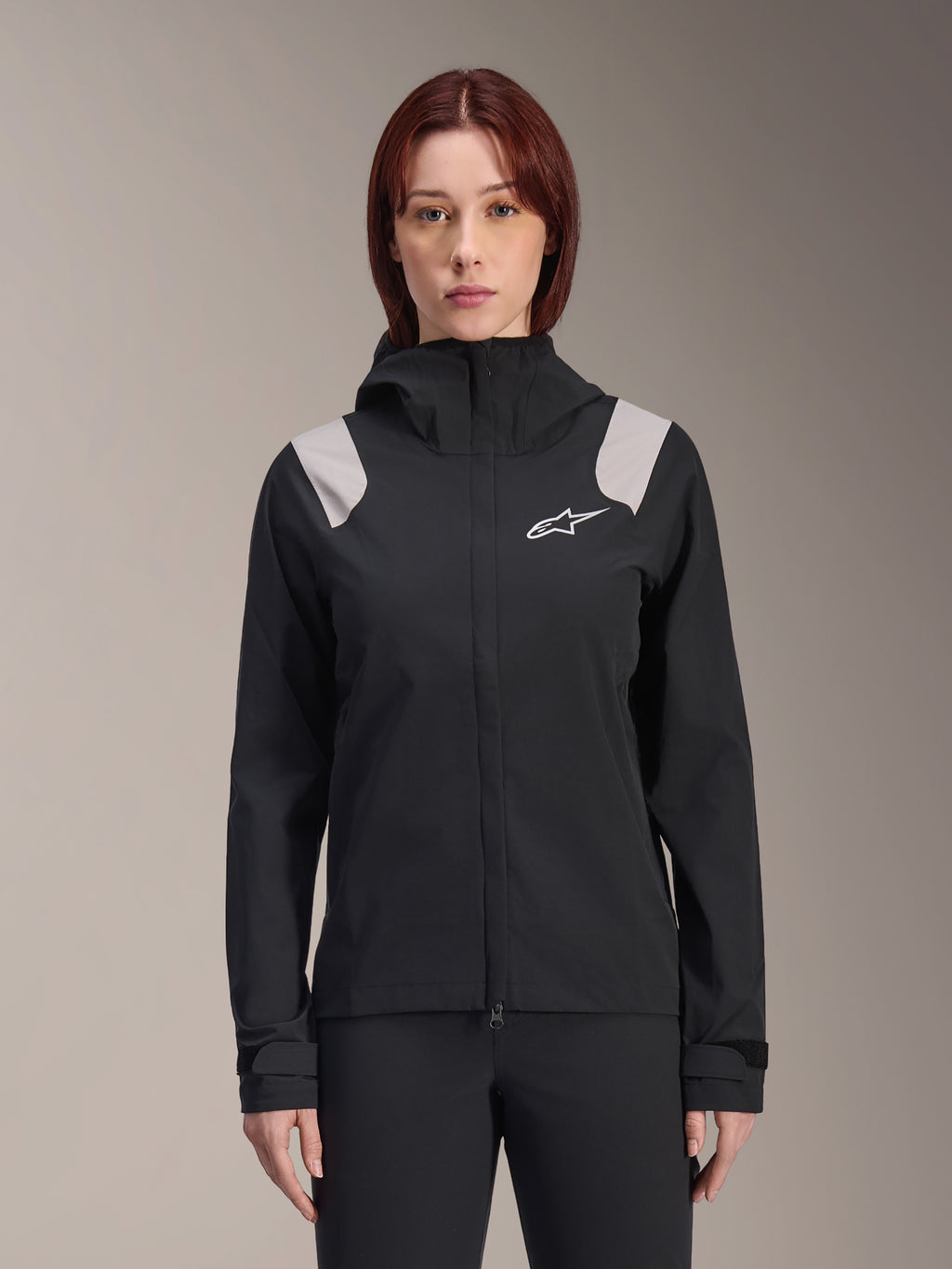 Alpinestars Stella A-Dura Rain Jacket, casaco de chuva de ciclismo feminino, preto com painéis cinzento-claro nos ombros, casaco técnico com capuz e logótipo branco no peito, punhos ajustáveis com Velcro, equipamento profissional para MTB e condução em tempo de chuva