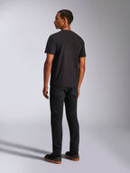 Alpinestars Ageless 2.0 CSF Tee, t-shirt de manga curta, preta, vista traseira num modelo masculino, usada com calças pretas e sapatilhas com sola de borracha, streetwear casual inspirado no desporto motorizado