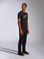 Alpinestars Ageless 2.0 CSF Tee, T-shirt de manga curta, preta com logótipo Alpinestars em verde brilhante, combinada com calças pretas e sapatilhas, streetwear casual inspirado no desporto motorizado