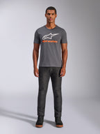Alpinestars Always 2.0 CSF Tee, t-shirt de manga curta, cinzento carvão com logótipo branco e texto laranja, vestida por um modelo com calças de ganga escuras, streetwear casual de motorsport
