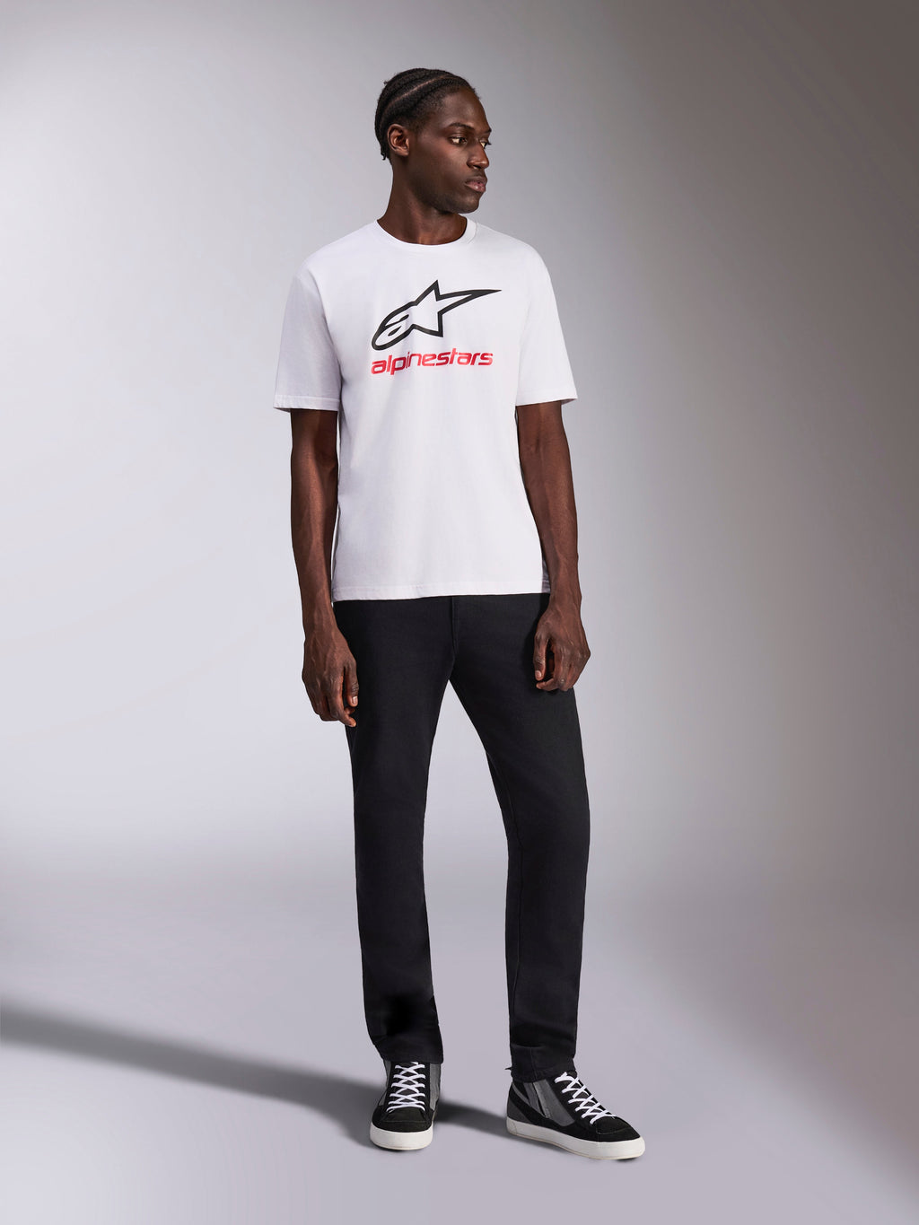 Alpinestars Always 2.0 CSF Tee, t-shirt de manga curta, branca, logótipo Astar preto e grafismo Alpinestars em vermelho, usada por um modelo com calças pretas e sapatilhas de cano alto, vestuário casual de motorsport