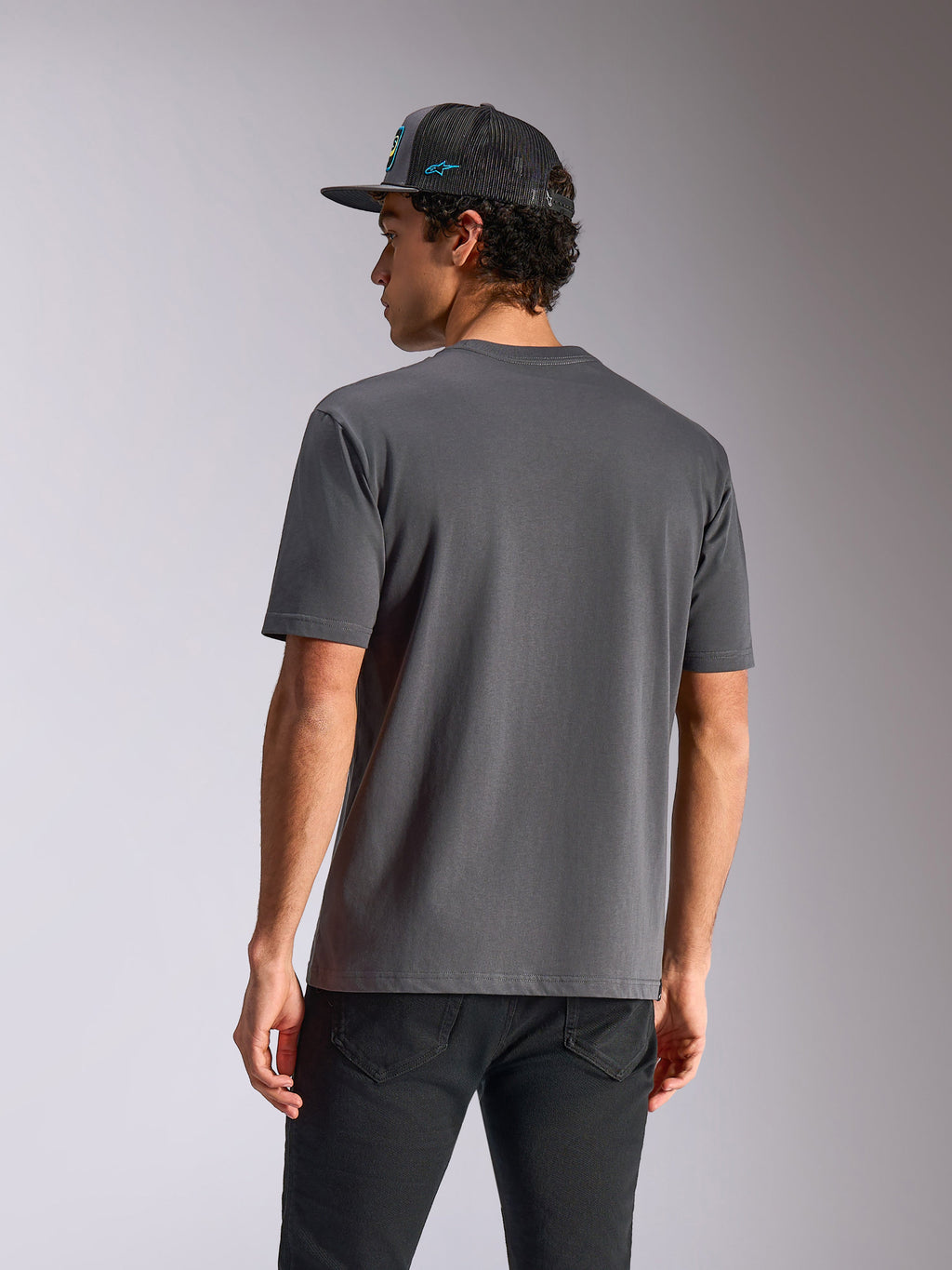 Alpinestars Blaze 2.0 CSF Tee, t-shirt de manga curta, cinzento carvão, vista traseira, usada com calças de ganga pretas e boné de rede, streetwear casual inspirado no desporto motorizado