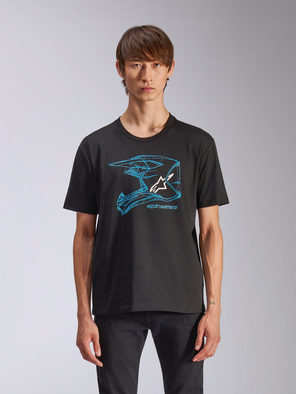 Alpinestars CSF Tee, t-shirt de manga curta, preta, grafismo de capacete de motocross azul com logótipo Astars branco, streetwear casual de inspiração motorsport, usada por modelo
