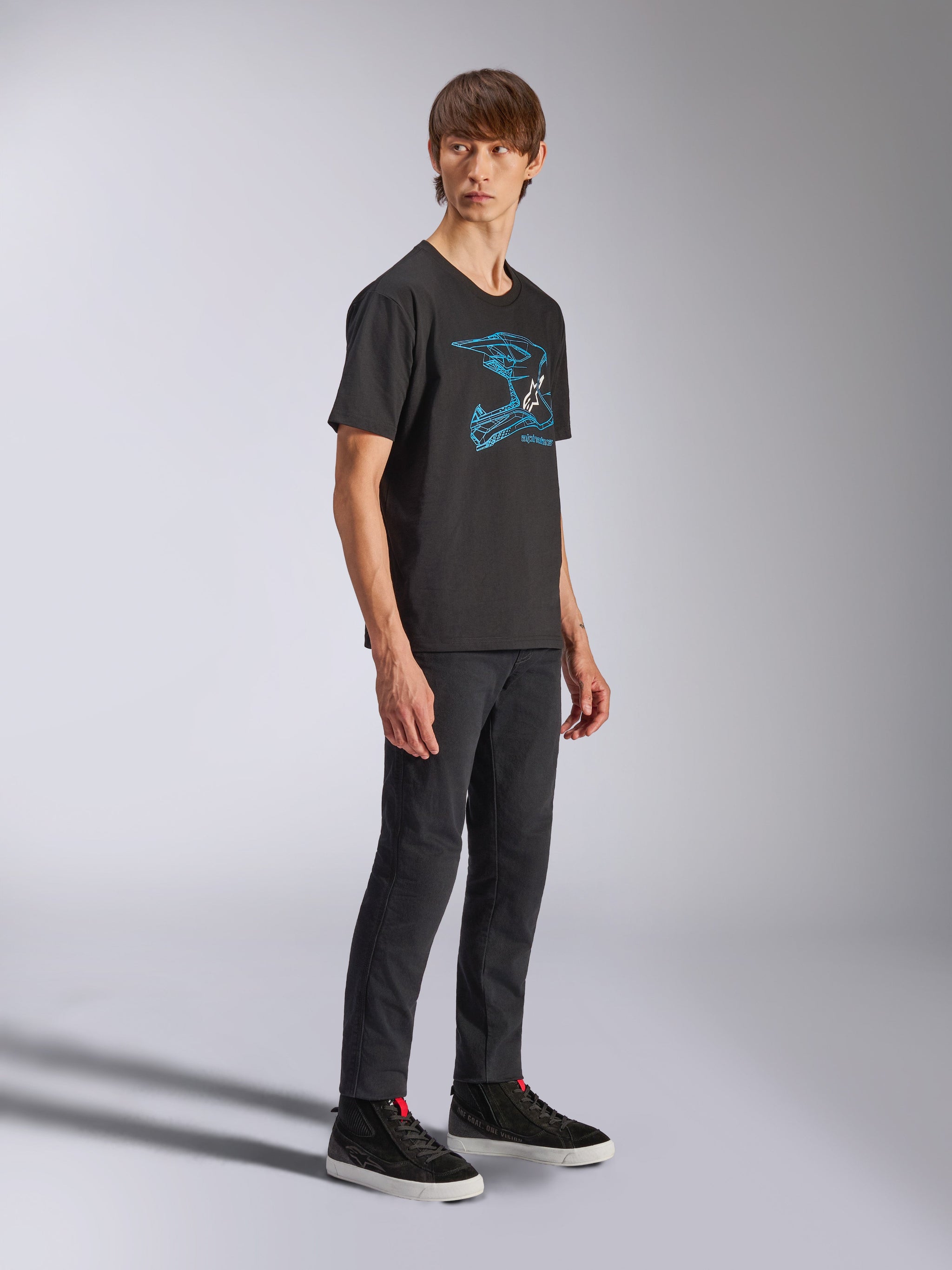 Alpinestars CSF Tee, Black Short Sleeve T-Shirt with Blue MX Helmet Graphic, worn by model with black pants and high-top sneakers, casual motorsport streetwear