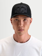Alpinestars Boné Trucker Heritage Patch, boné desportivo casual preto e cinzento, com aba curva, copa estruturada, parte traseira em malha e grande patch bordado com logótipo num modelo