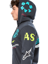 Alpinestars Variegate Hoodie, Gunmetal gray zip-front fleece, side profile of model, multi-logo artwork in neon yellow, light blue, and white, features 'AS' branding on sleeve and 'STARS' on hood, casual motorsport-inspired streetwear