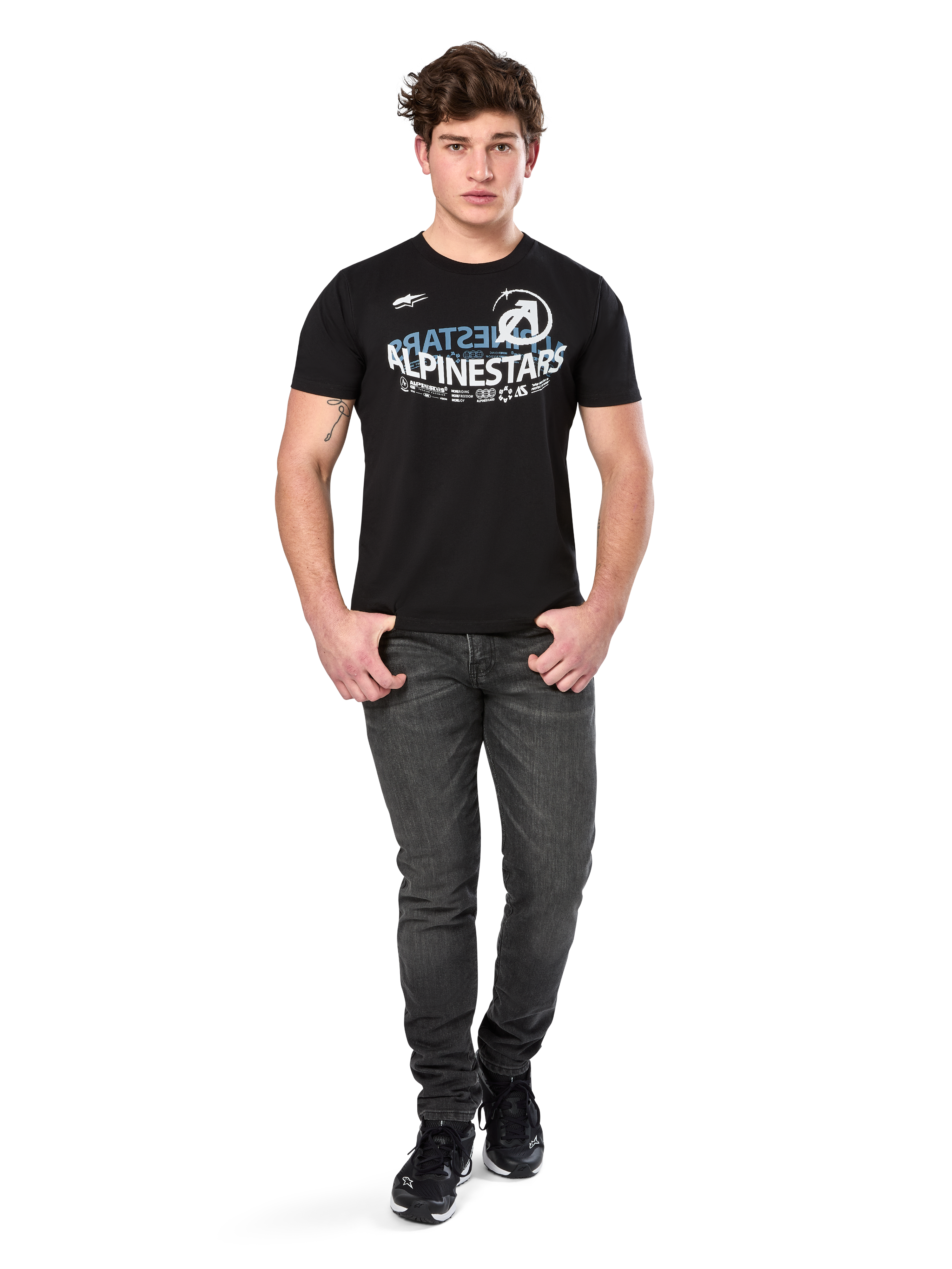 T-shirt Alpinestars Semicircle CSF, t-shirt de manga curta, preta com gráfico curvo em branco e azul claro no peito, vestida por modelo com calças de ganga cinzento escuro e sapatilhas pretas, streetwear casual de desportos motorizados