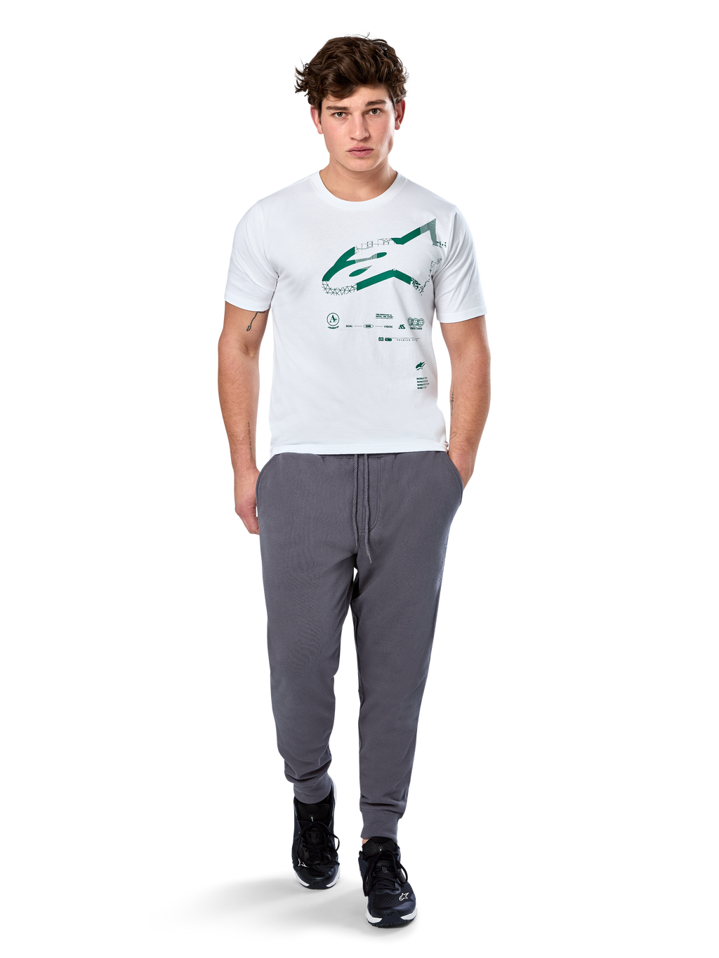 Alpinestars Geografica CSF Tee, t-shirt de manga curta, branca, logótipo Astars verde com gráfico geográfico multi-tech, acompanhada por calças de fato de treino cinzentas e sapatilhas pretas, streetwear casual de desportos motorizados