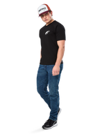Alpinestars Formulate Csf Tee, t-shirt de manga curta, preta com logótipo Astars branco no peito, vestida por um modelo com calças de ganga azuis, boné bordeaux e branco e sapatilhas pretas, streetwear casual inspirado no desporto motorizado