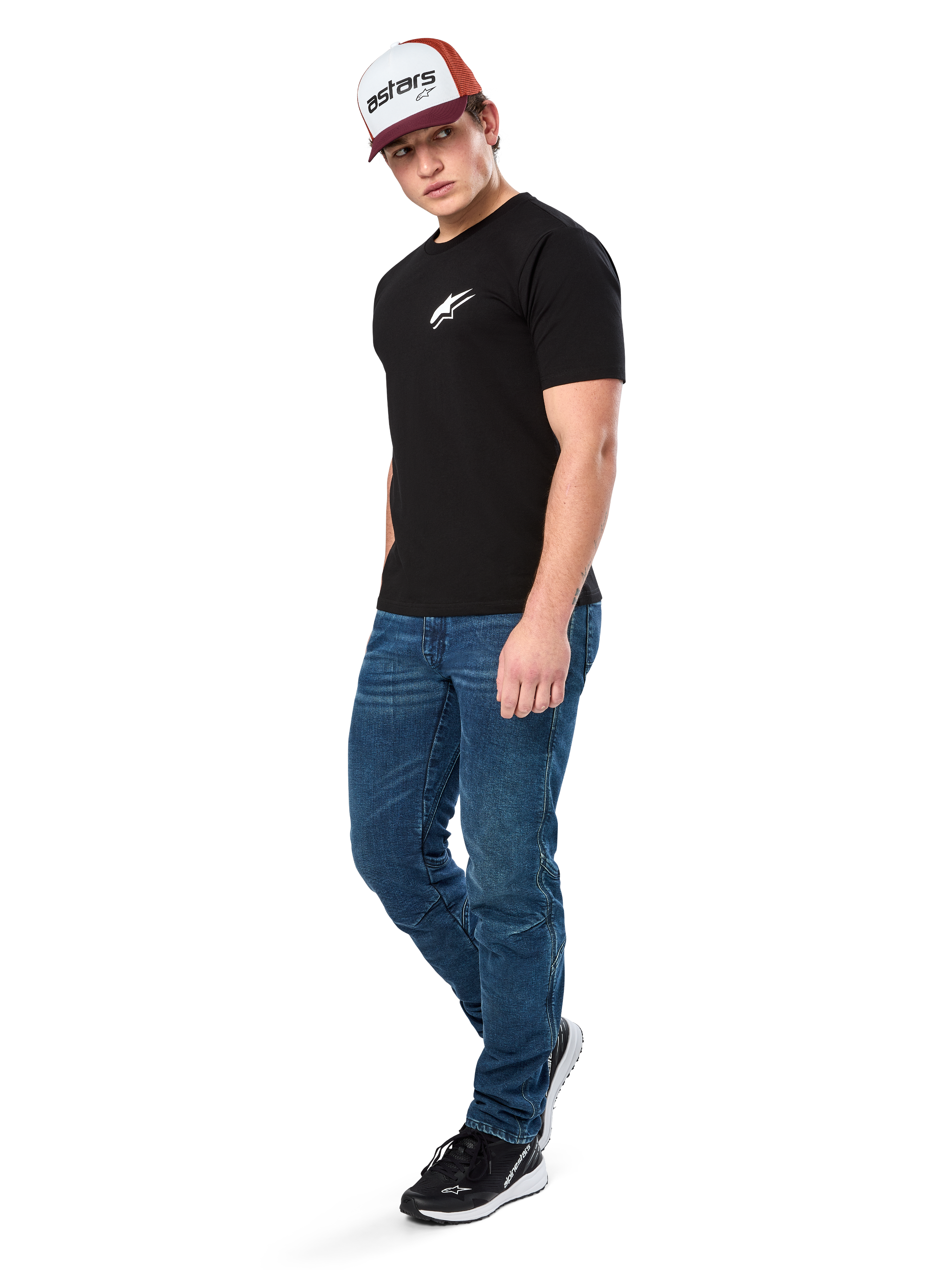 Alpinestars Formulate Csf Tee, t-shirt de manga curta, preta com logótipo Astars branco no peito, vestida por um modelo com calças de ganga azuis, boné bordeaux e branco e sapatilhas pretas, streetwear casual inspirado no desporto motorizado