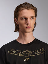 Alpinestars Luxo CSF Tee, t-shirt de manga curta, preta, logótipo Astars metálico dourado no peito, vestida por modelo masculino, design casual inspirado no desporto motorizado