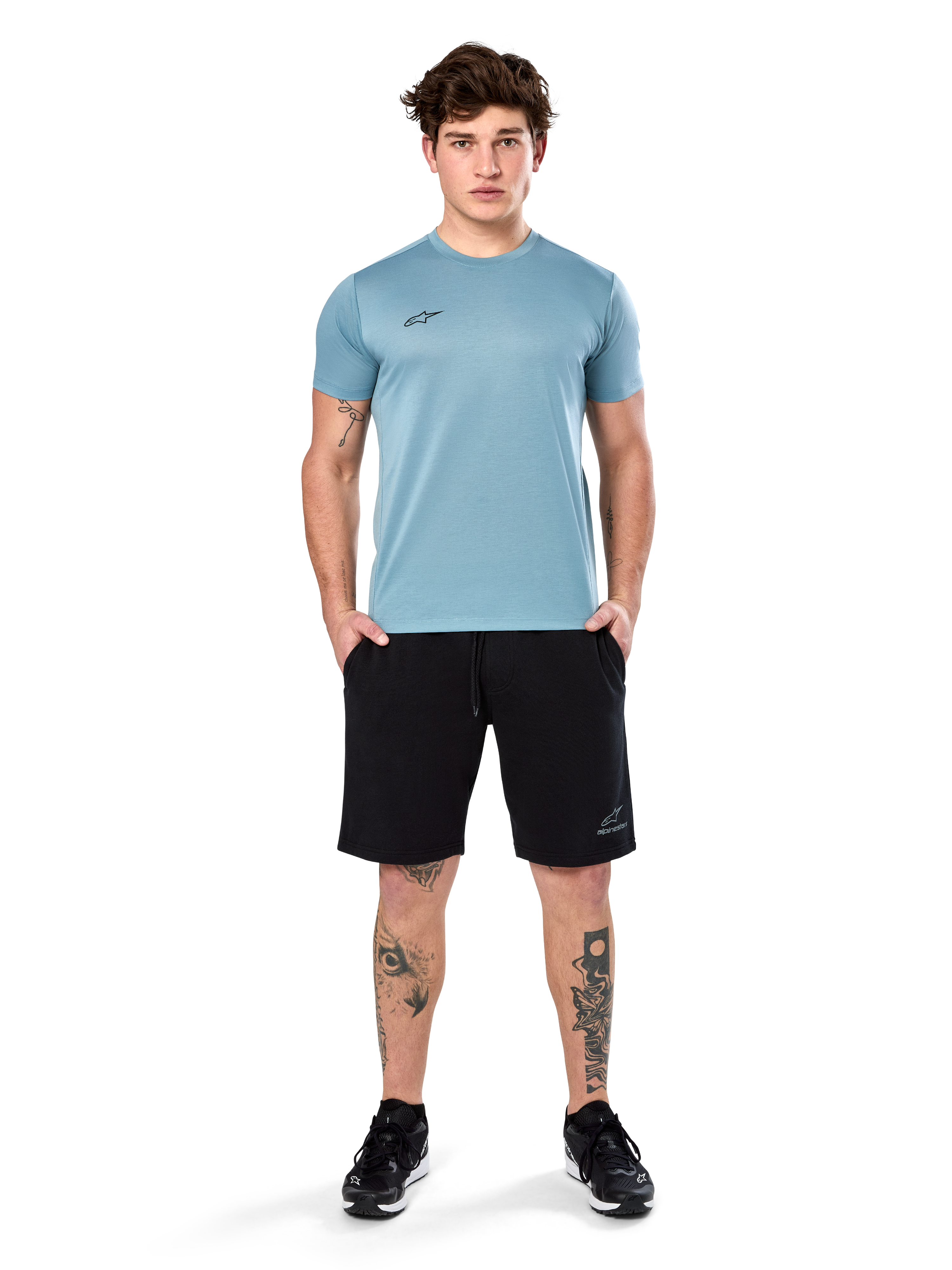 Alpinestars Point Performance Tee, t-shirt de manga curta, azul gelo, com um pequeno logótipo frontal preto, gola redonda, usada por um modelo com calções pretos e sapatilhas pretas, roupa desportiva casual com absorção de humidade